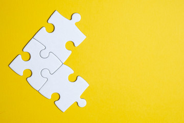 Three pieces of a puzzle united among themselves on a yellow background. Teamwork concept. - obrazy, fototapety, plakaty