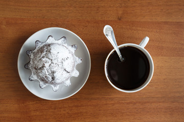 coffee mug and chocolate cupcake on a small plate. On brown wooden background. The view from the top