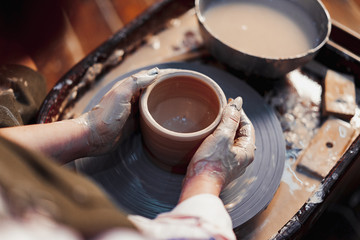Close up of Female Potter Hands Working on Pottery Wheel at Clay Studio With Clay. Making Handcrafted Crockery.