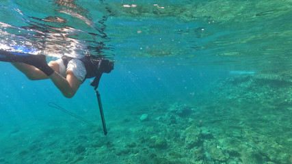 Underwater photo of spear fishing gun scuba diver in tropical exotic sea