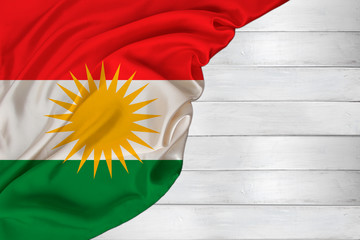 horizontal colored national flag of modern state Kurdistan, beautiful silk, white wood background,...