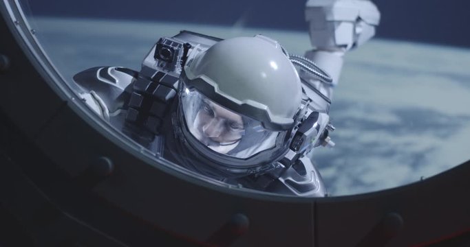 Astronaut floating by spacecrafts window