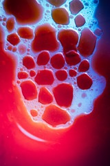 macro close-up photo of sparkling purple red carbonated water in bright lit clear blue oil creating...