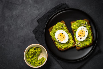 Avocado Sandwiches on black background.