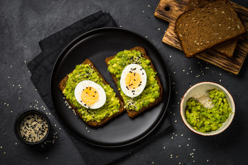 Avocado Sandwiches on black background.