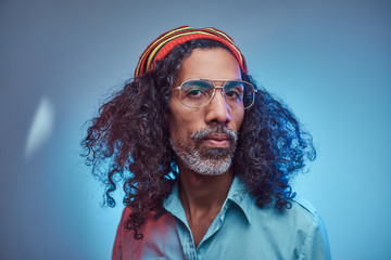 Studio portrait of African Rastafarian male wearing a blue shirt and beanie. Isolated on a blue...