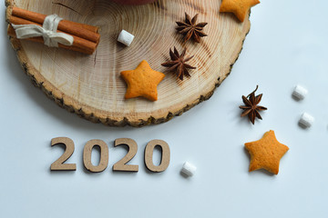 Christmas homemade gingerbread, milk, cinnamon, marshmallows, candies on a wooden plate by the window. Wooden numbers 2020.copy space, soft focus