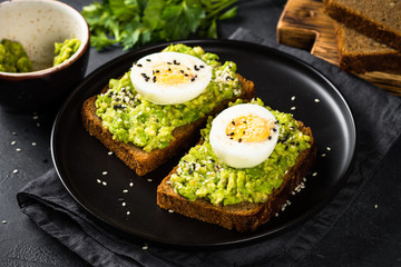 Avocado Sandwiches on black background.