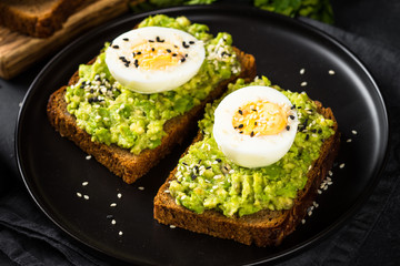 Avocado Sandwiches on black background.