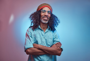 African Rastafarian male smiles and looks at the camera standing with his arms crossed. Studio...