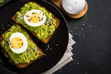 Avocado Sandwiches on black background.