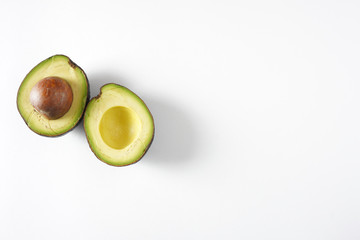 Two avocado halves on a white background with copy space