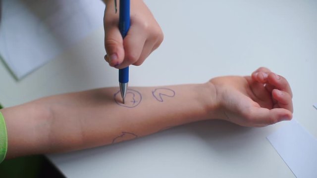 Close-up of a child's hand. The child draws a smiley sign.