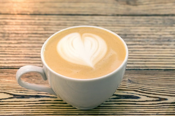 fragrant cappuccino coffee in a white Cup on a wooden table with a wooden background.