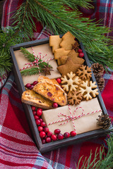 Homemade christmas cookies and wrapped presents with fresh cranberries in a wooden box