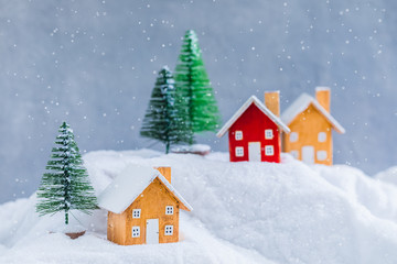 Fototapeta premium Miniature wooden houses on the snow over blurred Christmas decoration background, toned, daylight