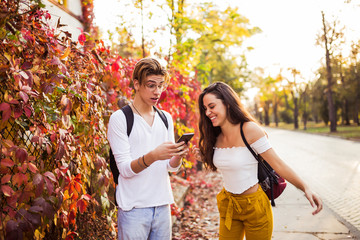 Happy joyful young couple laughing holding phone talking about funny online joke