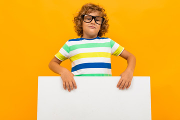 European curly boy with glasses holds a banner in his hands on a yellow background