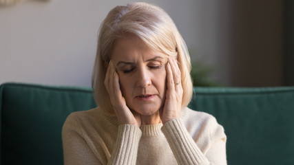 Closeup portrait aged woman touches temples suffers from migraine