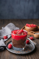 Superfood healthy vegan dessert, dark cocoa chia seed pudding with raspberry puree, topped with fresh berries and chocolate shavings in a glass jar