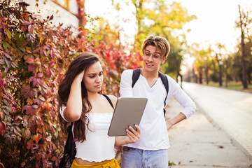Naklejka premium Two happy friends using a digital tablet while enjoying a day outdoors together