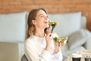 Woman eating healthy vegetable salad in office