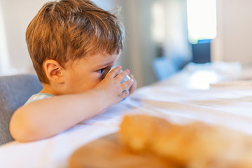 Fototapeta premium Moustache breakfast. Portrait of boy drinking milk on an open cup. Kid or blonde happy boy eating at table. Childhood and happiness, independence. Breakfast, morning, family