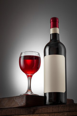 Blank beige label on the bottle of red wine and wineglass on the wooden table. Wine bottle mockup with clipping path.