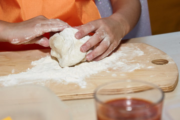 The kid 's learning to make pizza from the dough.