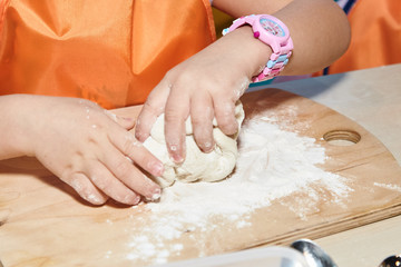 The kid 's learning to make pizza from the dough.