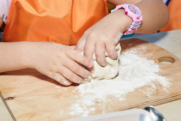 The kid 's learning to make pizza from the dough.