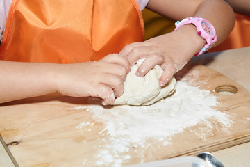 The kid 's learning to make pizza from the dough.