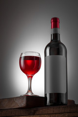 Blank black label on the bottle of red wine and wineglass on the wooden table. Wine bottle mockup with clipping path.