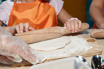 The kid 's learning to make pizza from the dough.