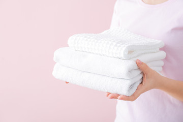 Woman holding clean towels on color background