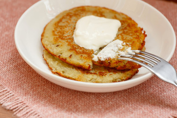 On a white plate lie two potato pancakes draniki - a traditional dish of Belarusian or Slavic cuisine. Dish of potato: hash Browns.