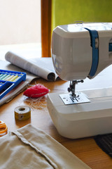 Work-space for sewing at home with sewing machine and accessories on table in daylight