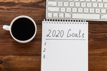 Obraz na płótnie Canvas Business concept of top view 2020 goals list with notebook, cup of coffee over wooden desk