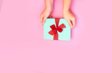 Gift box in woman's hands on a pink background. Surprise for Mother's Day, Valentine's Day or Women's Day.