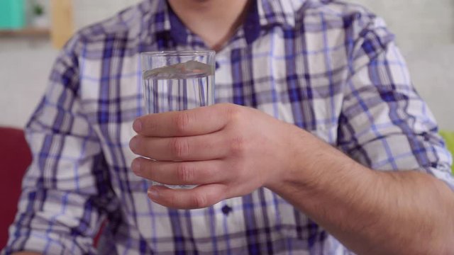 shaking hands of a man holding a glass of water close up