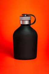Frasco negro en fondo naranja 