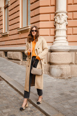 Fototapeta na wymiar fashion blogger outfit details. fashionable woman wearing beige trench coat, black jeans, slingback ankle shoes and trendy handbag. detail of a perfect fall fashion outfit.
