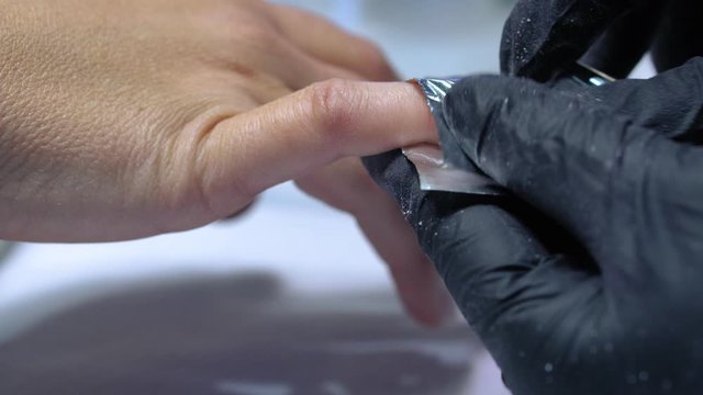 The procedure for removing gel polish from nails  in progress. Gel nail polish remover foils on woman's hands.