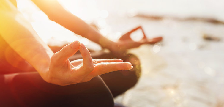 Unrecognizable Woman practicing yoga lesson in lotus position doing Ardha Padmasana exercise, closeup of body part with sunny light. Concept of biohacking, meditation, breathing, mental health Banner 