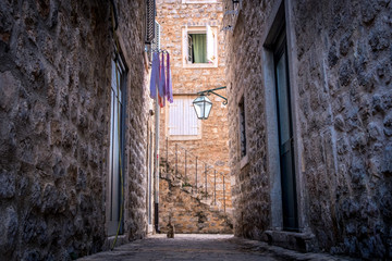 Fototapeta premium A cozy courtyard in the old city of Budva. Drying clothes, domestic cat sitting on the pavement