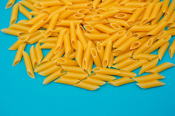 Pasta penne rigate on blue background. Top view, copy space