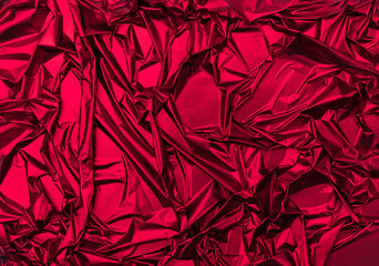 Shiny crumpled surface of vibrant red foil for textured holiday background. Backdrop for your...