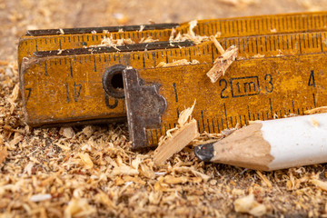 Carpentry measure in sawdust on a wooden table. Small carpentry work in a home workshop.