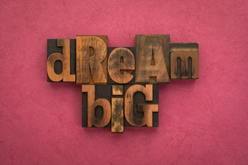 Dream big, phrase written with vintage letterpress printing blocks on textured  pink background
