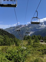 Empty chairlifts in the French Alps during a summer day. Cable car. Forest, trees, rocky mountains.